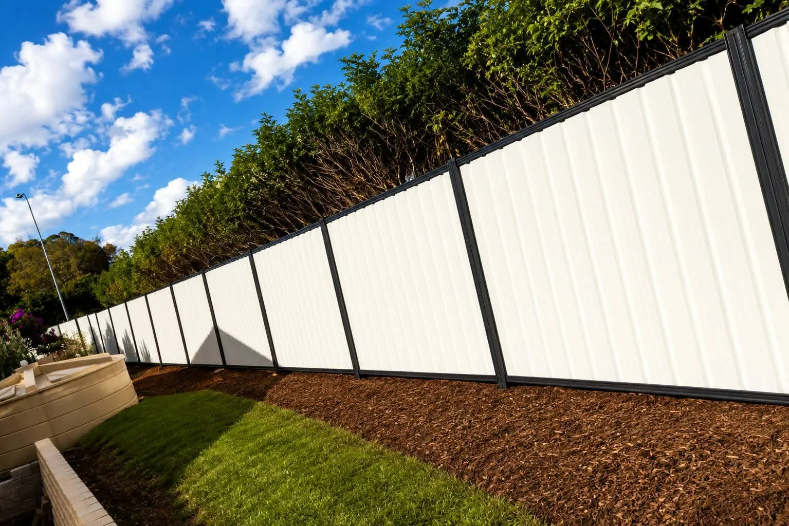 White fencing with dark posts along landscaped residential boundary